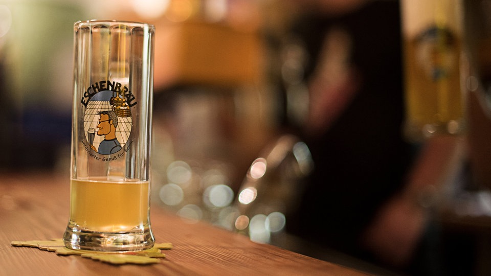 Bierglas und -Flasche auf einem beleuchteten Tresen