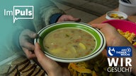 Ein Teller mit Suppe wird überreicht