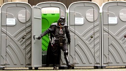 Mann im Darth-Vader-Kostüm verlässt zu Karneval eine mobile Toilette 