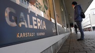 Eine Passantin betrachtet ein Schaufenster von Karstadt Kaufhof in Bielefeld.