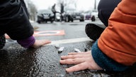 Demonstranten haben sich mit den Händen auf einer Straße festgeklebt