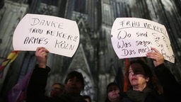 Zwei Frauen vor dem Dom mit Spruchpostern