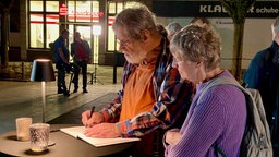 Trauernde tragen sich in Kondolenzbuch ein 