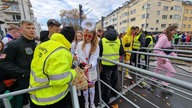 Sicherheitskräfte mit Warnwesten kontrollen Tschen von Feiernden.