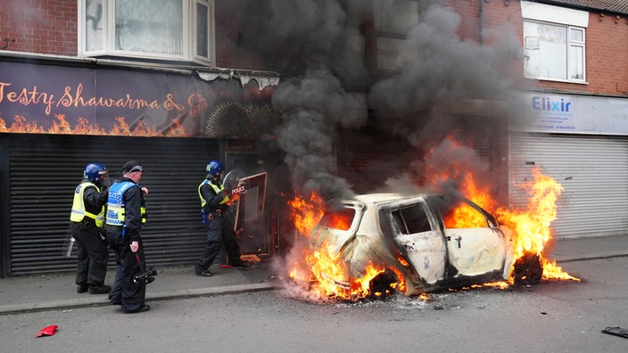 Sicherheitskräfte an einem brennenden Auto in Soutport