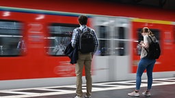 zwei junge Menschen stehen am Bahnsteig