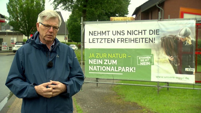 Hans Jürgen Wessels vom Förderverein Nationalpark Senne-Eggegebirge e.V. vor einem Protest-Plakat