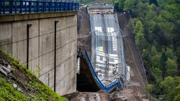 Nach der erfolgreichen Sprengung liegt die Rahmedetalbrücke auf dem Boden, Teile der Fahrbahn sind zu sehen. Am Tag nach der Sprengung der Talbrücke Rahmede an der Autobahn 45 in Lüdenscheid sind die Aufräumarbeiten bereits in Gang gekommen.