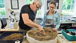 Archäologe Hans-Peter Schletter und Restauratorin Eileen Wolff sichern eine rund 3000 Jahre alte Urne aus der späten Bronzezeit