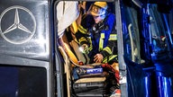 Ein Feuerwehrmann untersucht die Fahrerkabine eines Lastwagens