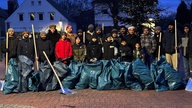 Männer stehen in Bielefeld aufgereiht mit Müllsäcken.