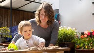 Mutter spielt mit Kind im Sandkasten