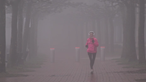 Eine Joggerin läuft durch dichten Nebel