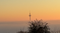 Sicht auf einen Turm bei Sonnenuntergang im Nebel