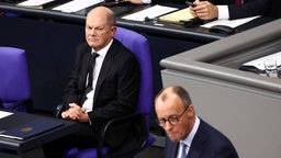 Olaf Scholz schaut kritisch auf Redner Friedrich Merz 