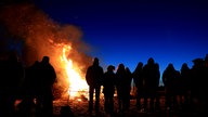 Zahlreiche Menschen stehen vor einem Osterfeuer