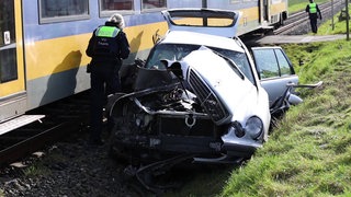 Beschädigtes Auto neben einem Zug