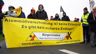 Menschen beklagen auf einem gelben Banner, dass Atommüllverschiebung keine Entsorgung sei. Sie fordern ein sicheres Endlager. 