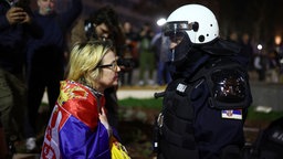 Eine Demonstrantin spricht mit einem Polizisten während einer Großdemonstration gegen den populistischen Präsidenten Vucic und seine Regierung in der Innenstadt von Belgrad