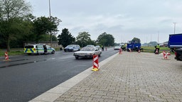 Man sieht auf einer abgelegenen Straße Polizeiautos, sowie zivile Fahrzeuge.