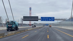 Fahrbahn der A1 mit einem Autobahn-Schild und Baustellenfahrzeugen.