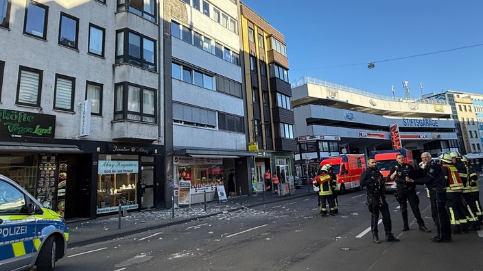 Polizisten und Feuerwehr vor der abgebrochenen Hauswand in der Bonner Innenstadt