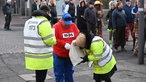 Sicherheitsmitarbeiter kontrollieren einen Besucher.