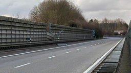 Zu sehen ist eine leere Autobahn, auf die an einer Stelle ein Stück der Schallschutzwand am Rand ragt