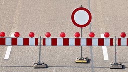 Auf dem Foto ist eine Autobahn mit mehreren Fahrbahnen, vor der mit einem Zaun und einem Schild eine Sparrung markiert ist.