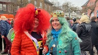 Eine Frau verkleidet als Clown mit großer roter Perücke und eine Frau verkleidet als Meerjungfrau feiern Weiberfastnacht in Bad Münstereifel.