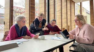 Das Bild zeigt eine Frau, die den Teilnehmerinnen Smartphones erklärt