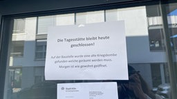 Ein weißer Zettel an der Tür einer Tagesstätte, auf dem steht, dass die Tagessstätte geschlossen ist, da eine alte Kriegsbombe auf einer Baustelle gefunden wurde.