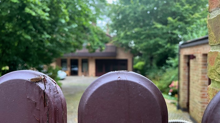 Ein Grundstück mit einem sandsteinfarbenen Backsteinhaus. Fotografiert aus Richtung der Einfahrt