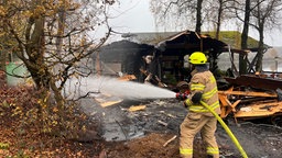 Ein Feuerwehrmann löscht einen Brand in einer Gaststätte in Hückeswagen