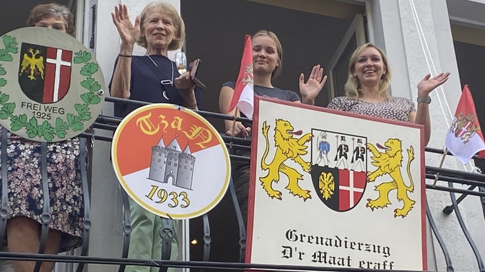 Frauen winken von einem Balkon herab