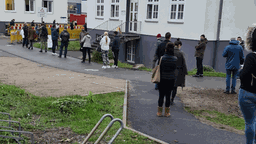 Etwa 100 Menschen warten vor der Teststelle der Uniklinik Köln, um einen Coronatest machen zu lassen.