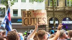 Ein Mann hält ein Schild mit der Aufschrift "Ihr queeren Cuties" hoch