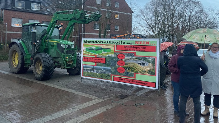 Menschengruppe mit Traktor und Protest-Banner.