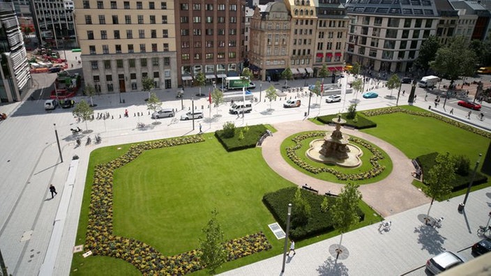 Ein Blick von oben auf einen Platz in der Mitte mit Wiese und einem Brunnen