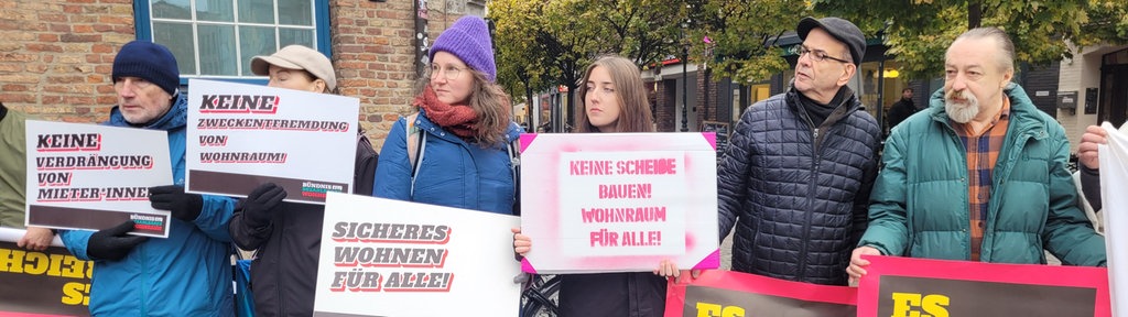 Mehrere Menschen nebeneinander mit verschiedenen Protestplakaten