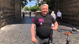 Michael Seffen trägt ein schwarzes T-Shirt mit der Aufschrift Veedelskümmerer.