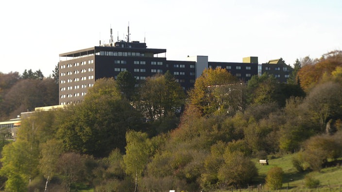 Hinter Bäumen ist auf einem Hügel die Eifelhöhenklinik in Marmagen zu erkennen.