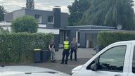 Drei Polizisten stehen vor dem Tatort