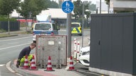 Ein Feuerwehrmann schaut in einen offenen Bodenschacht am Einsatzort.