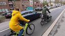 Zwei Radfahrer auf einer Straße in Mönchengladbach, gerade werden sie von einem Auto überholt.