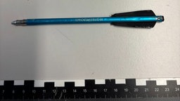 Ein Pfeil der Armbrust liegt auf einem Tisch oberhalb eines Lineals und misst 15 cm.