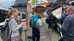 Menschen warten vor dem Ersatzbus, der von Köln nach Frankfurt fährt.