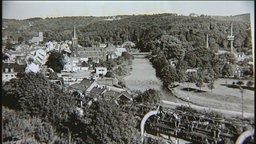 Man sieht eine alte Aufnahme, zu sehen ist die Schwebebahn, sowie zahlreiche Häuser.