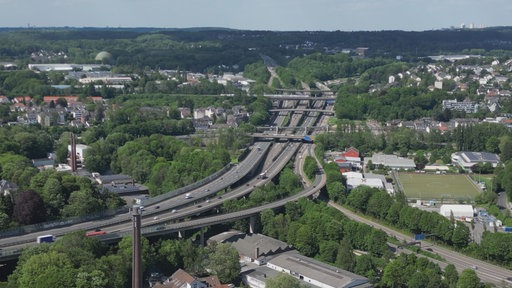 Man sieht von weiter Perspektive das Sonnborner Kreuz. Es ist umgeben von Häusern, sowie zahlreichen Bäumen.