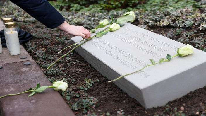 Auf einer Gedenktafel, welche an den Terroranschlag in Solingen vergangenen August erinnern soll, werden weiße Rosen abgelegt.